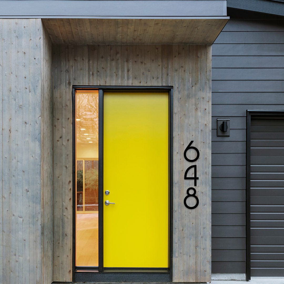 A black door with the number 648 printed in a large, white sans-serif font on the side, mounted on a wooden entrance with a yellow panel.
