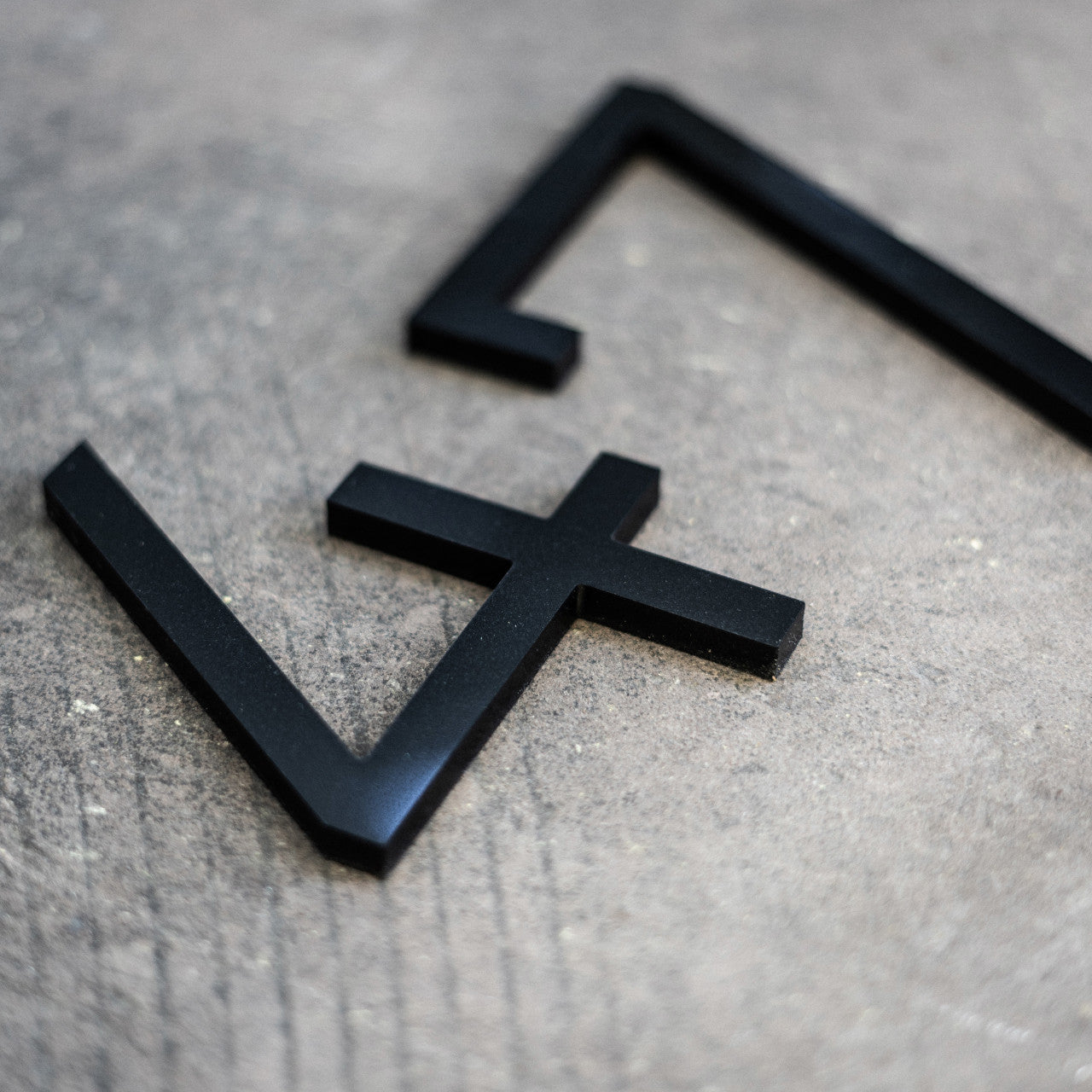 Black house numbers in a modern sans serif style placed on a grey background.