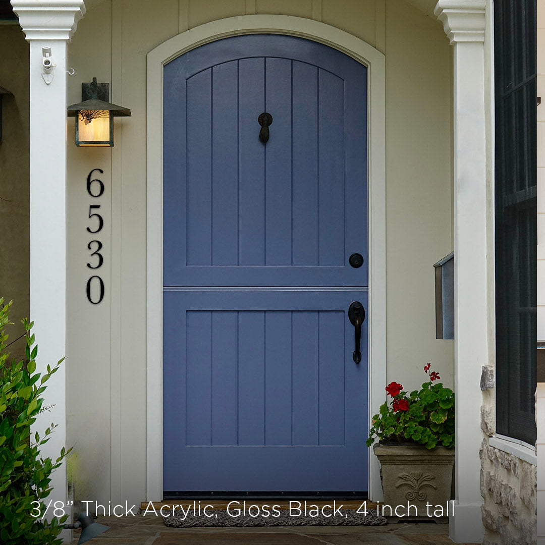 Blue front door of a house with white trim and black 4 inch metal address numbers in a traditional style.