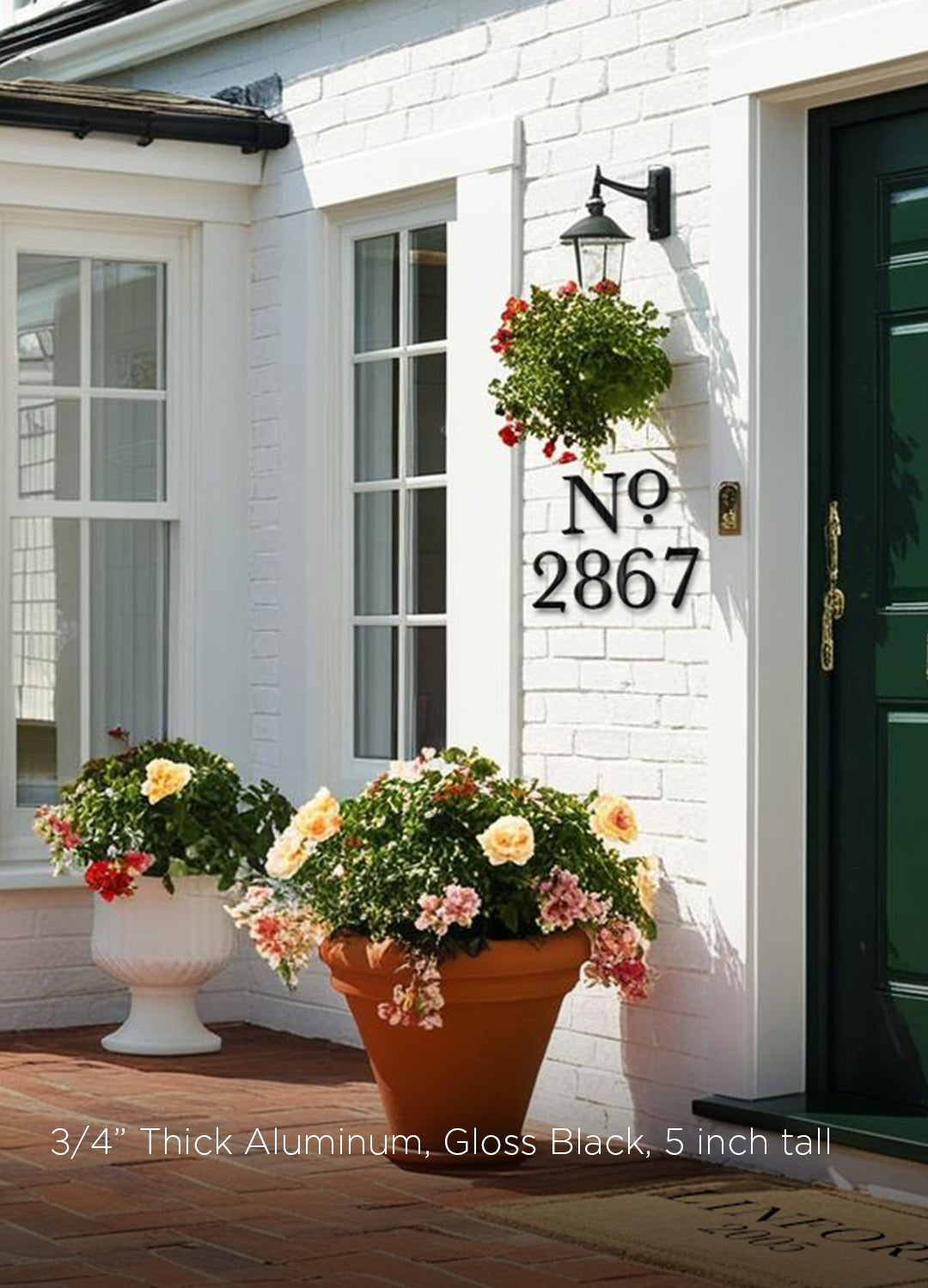 House number with a "No" abbreviation in black metal '2867' on a white brick wall with potted flowers.