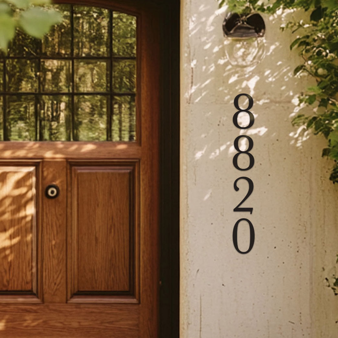 black 8 inch house number '8820' on a white wall next to a wooden door with glass panels.