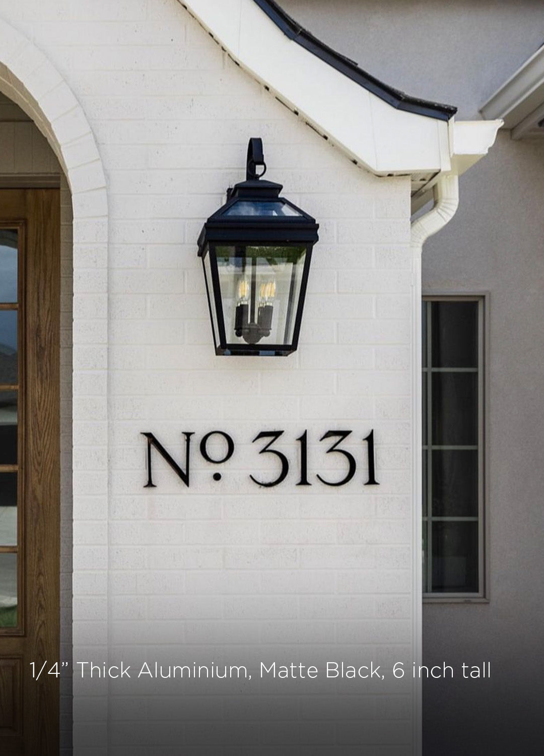 House exterior with a black lantern and modern black metal house numbers 'No 3131' on a white wall.
