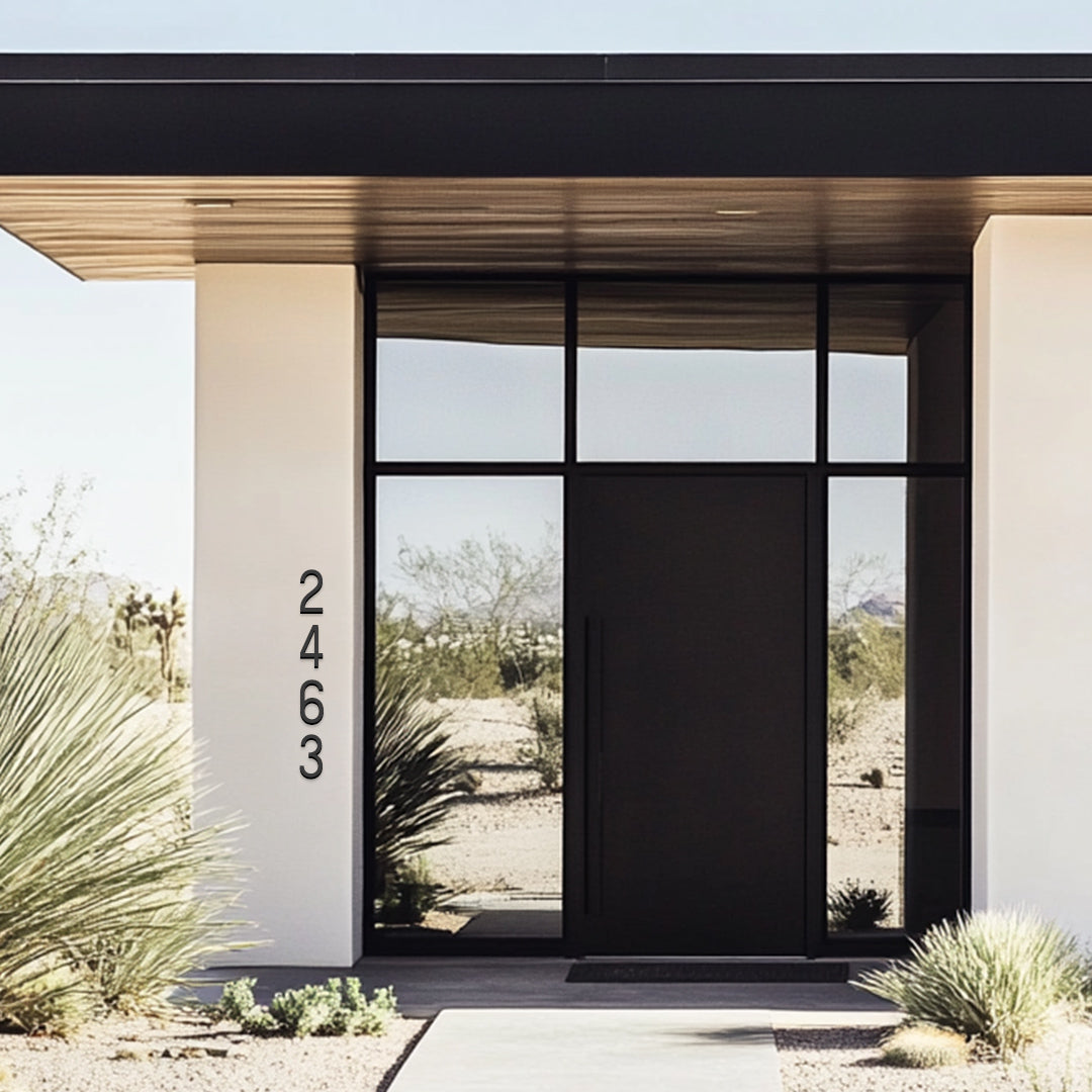 Tall and narrow house numbers in black modern style. Modern white stucco house with black door and flat black roof