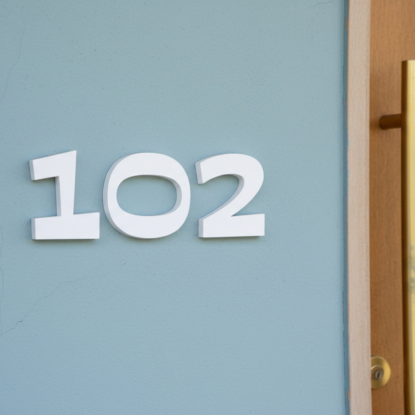 White house numbers '102' on a light blue door.