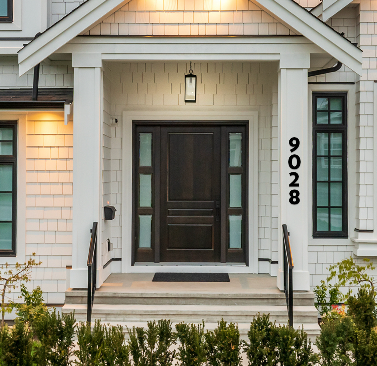 A white house with black numbers '9028' mounted on the front door