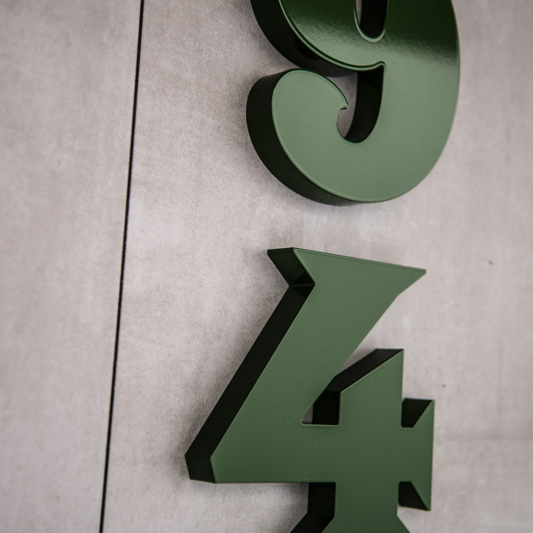 Green house numbers on a concrete house