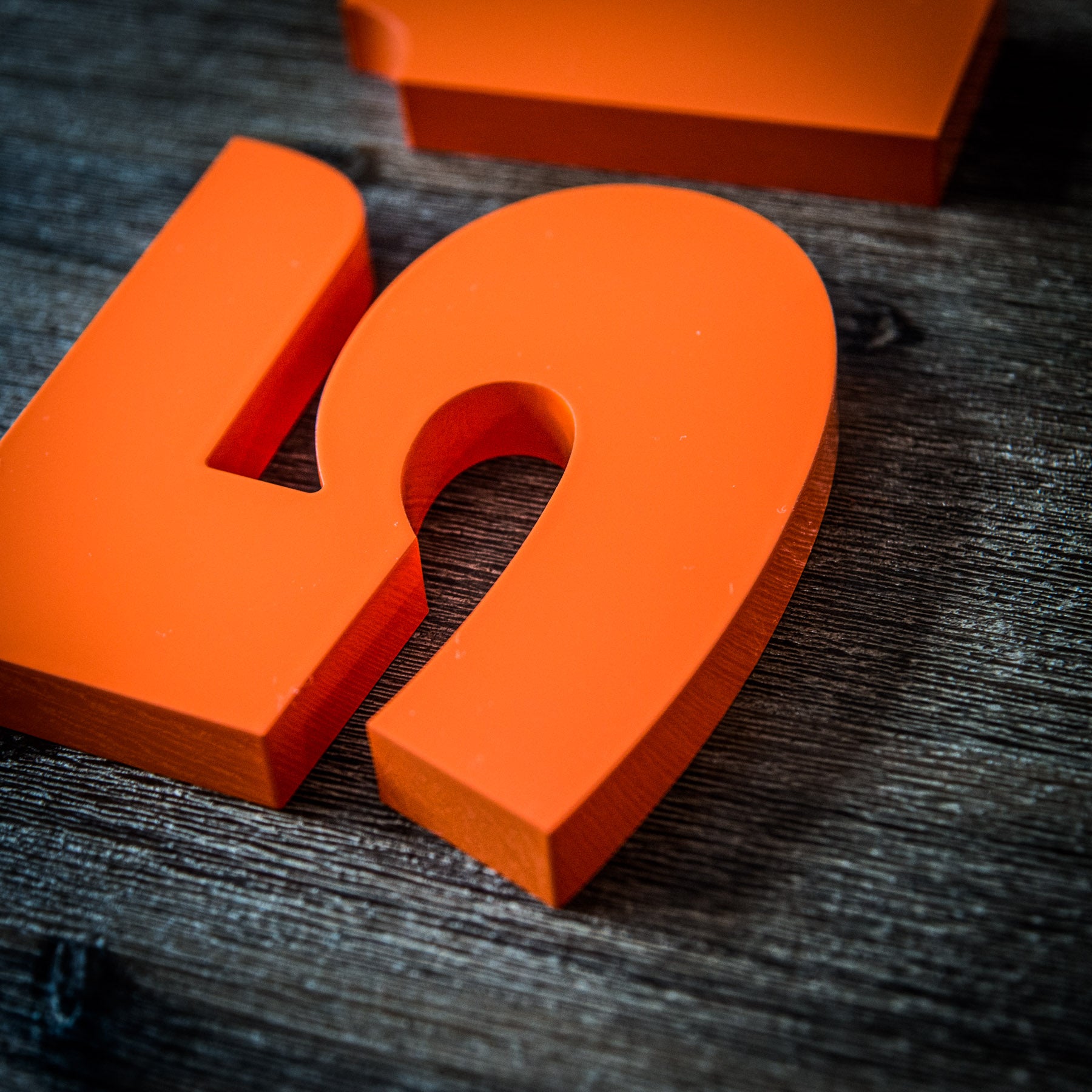 Orange house numbers on a wood background