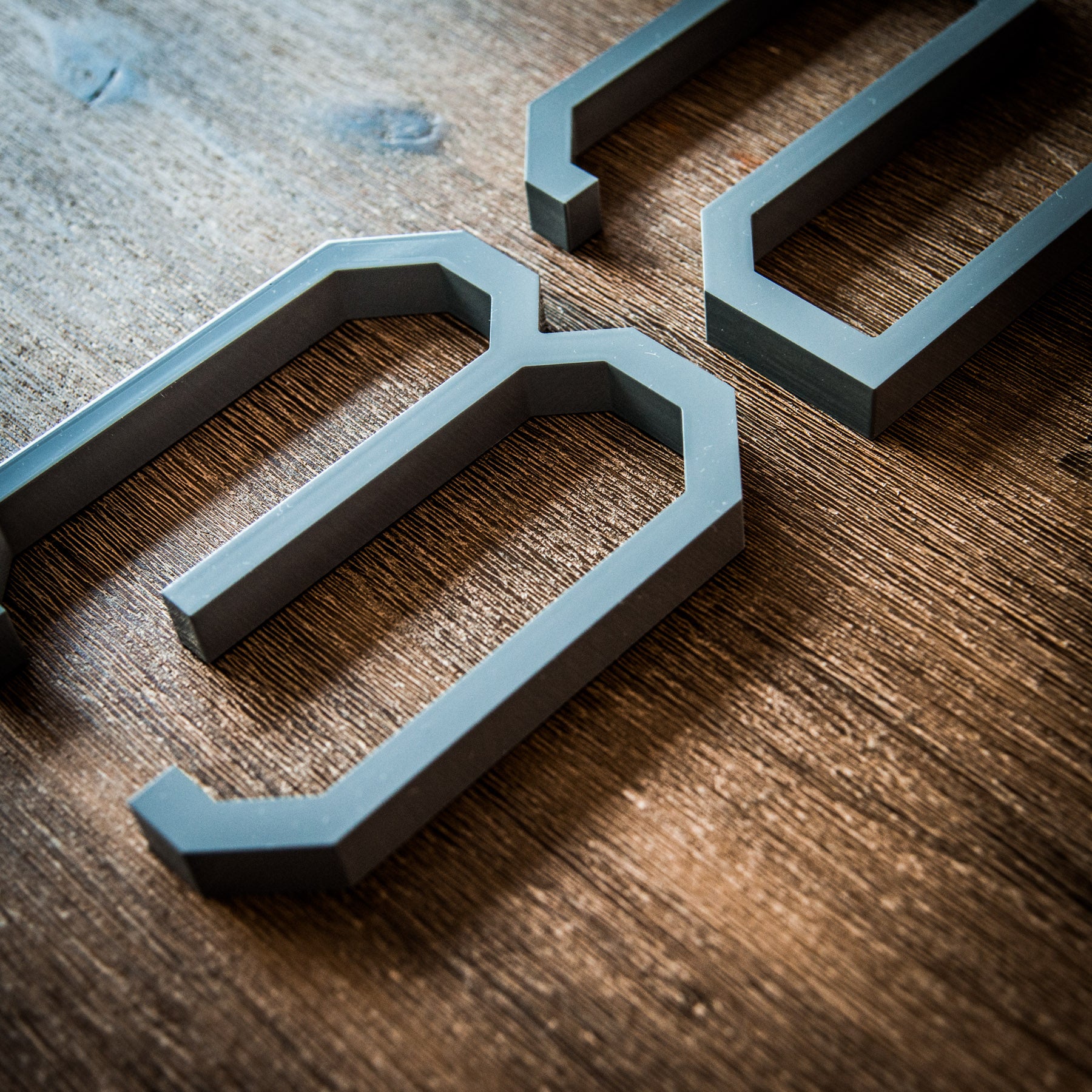Grey modern house numbers on a wood surface