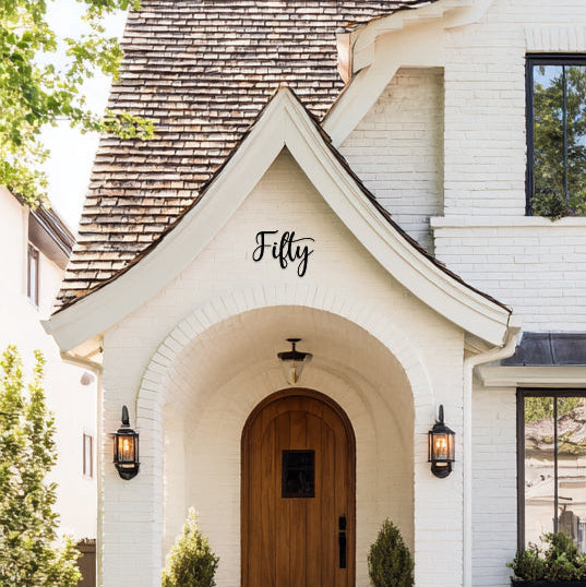 White house with a decorative front porch and 'Fifty' sign above the door.