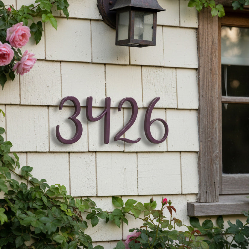 Purple House numbers '3426' on a white wooden wall with flowers and a lamp.