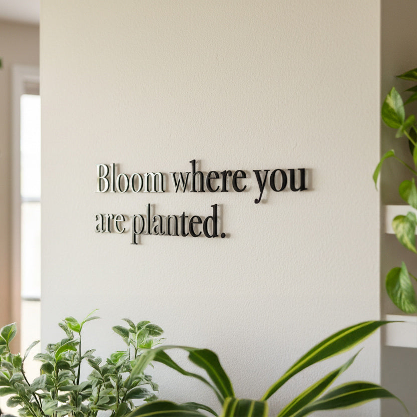 Decorative wall art with motivational quote 'Bloom where you are planted.' in a room with plants.