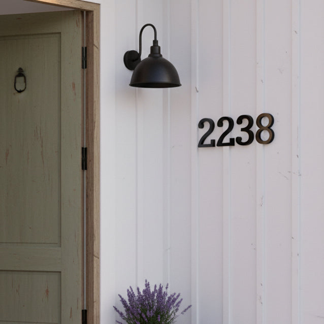 black House number '2238' on a white wooden door with a wall light fixture.