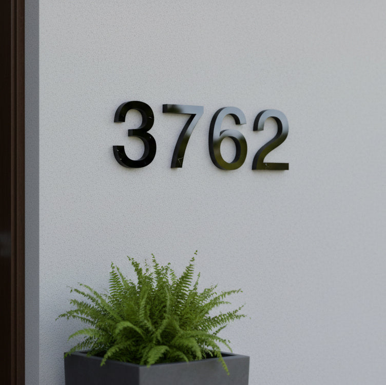 black House number '3762' on a wall with a potted plant below.