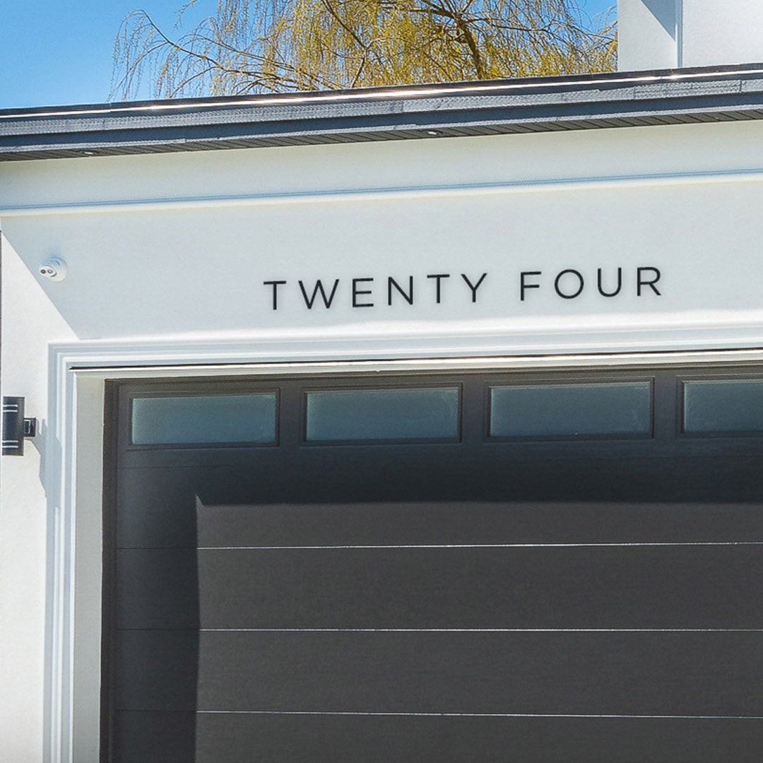 Garage door with 'TWENTY FOUR' address spelled out in black metal house numbers