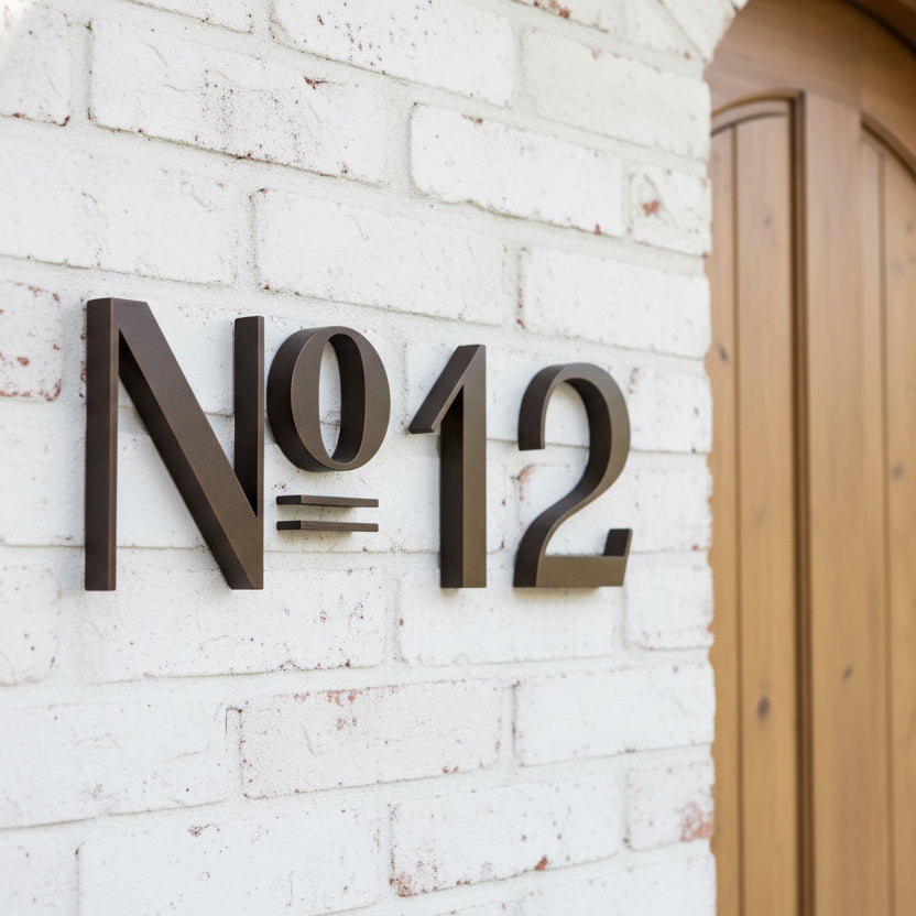 Decorative house number 'N012' on a white brick wall.
