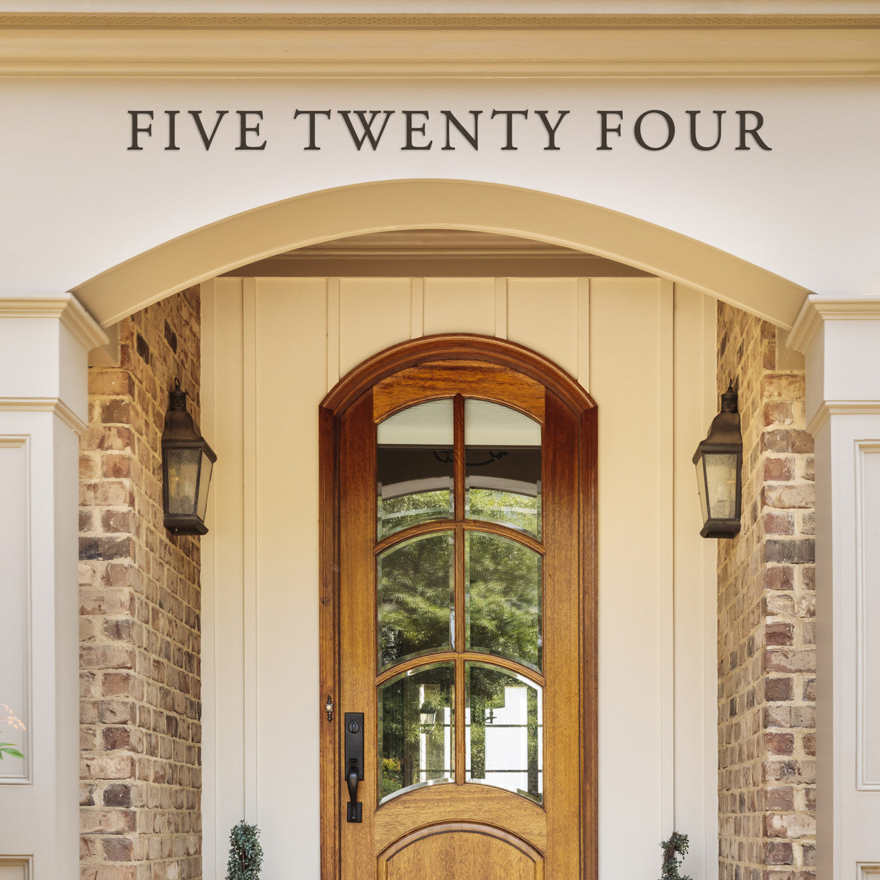 A traditional style house number 'FIVE TWENTY FOUR' mounted above an arched front door with a brick column on either side.