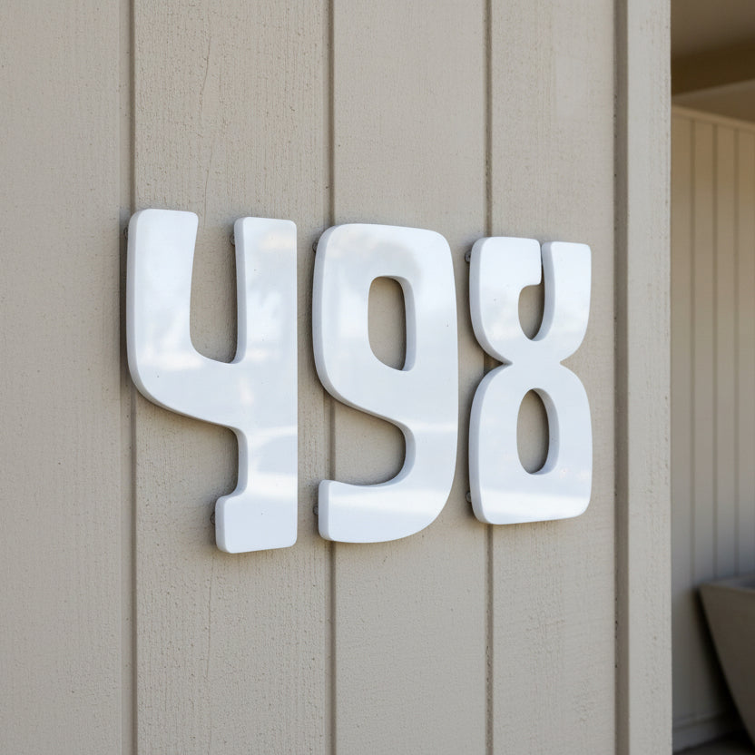 White 3D house numbers '498' mounted on a beige vertical siding wall.