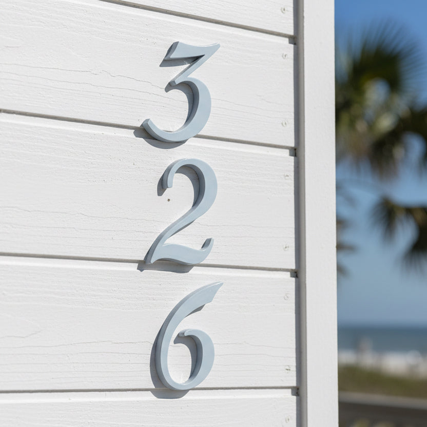 House numbers '326' on a white wall with a blurred outdoor background