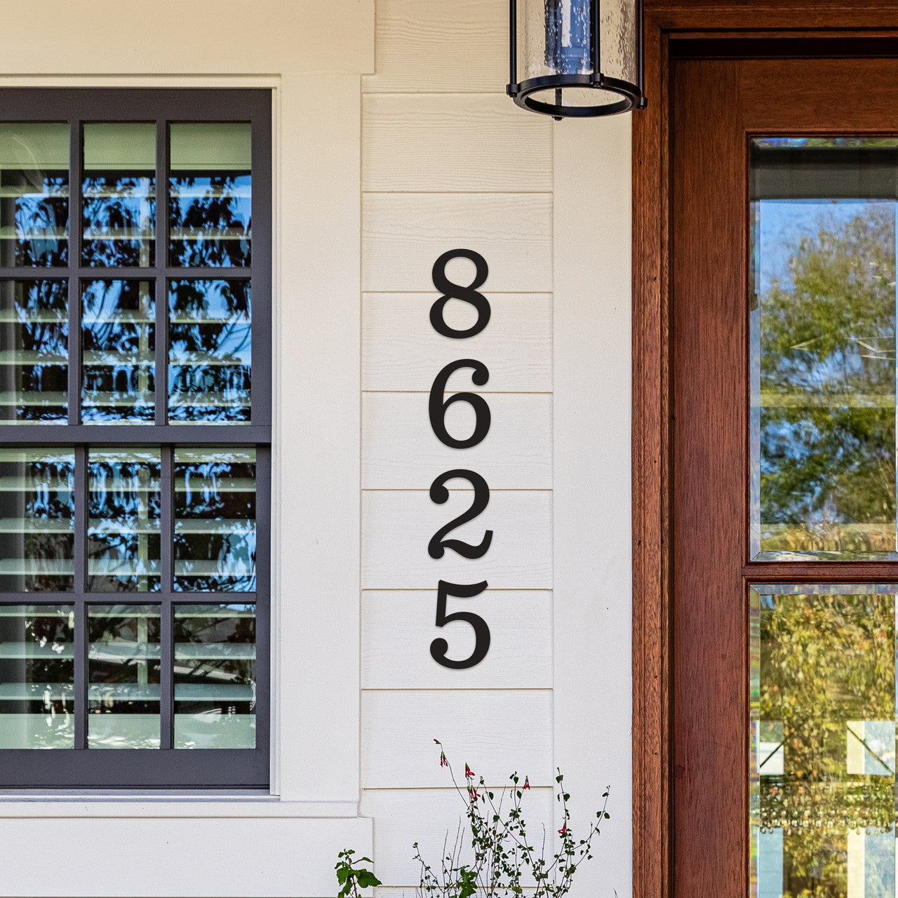 Black house numbers '8625' mounted on a white wall beside a window