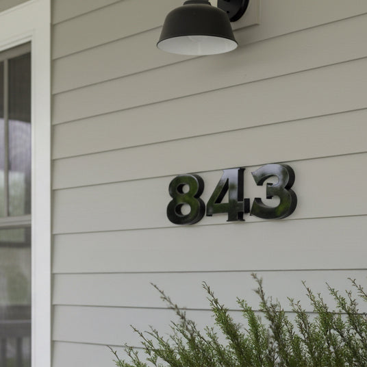 House number '843' on a light-colored wall with a lamp above.