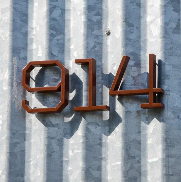 House numbers '914' on a textured metal surface