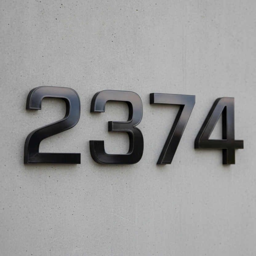 Black metal house numbers '2374' mounted on a light gray textured concrete wall.