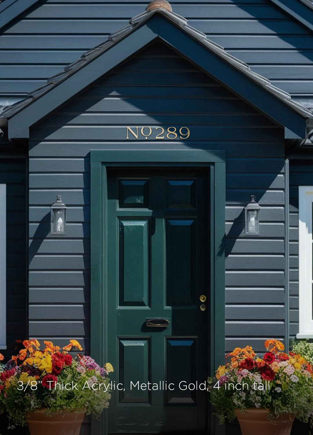 Dark blue house with a green door and decorative flowers in front with solid brass house numbers above door in a farmhouse style address numbers
