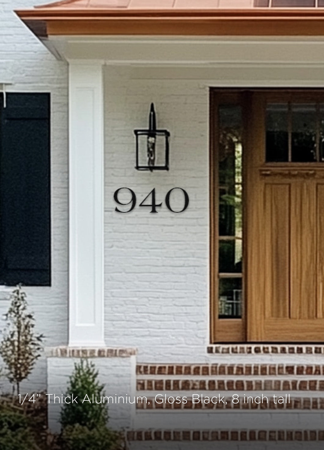 House exterior with a wooden door and farmhouse style house number '940' on a white brick wall.