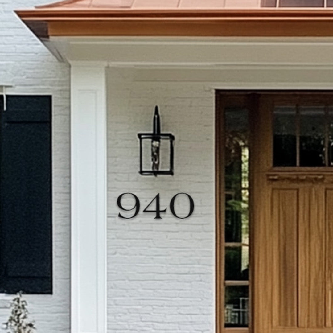 House exterior with a wooden door and farmhouse style house number '940' on a white brick wall.