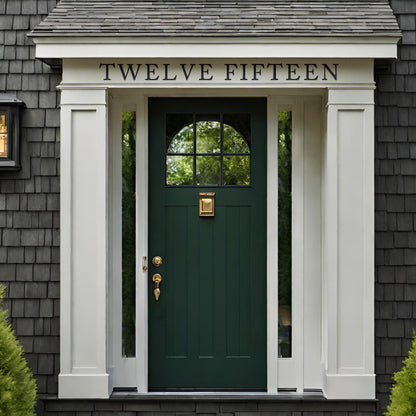 Traditional house with grey shingle shakes with white trim green front door. Spelled out address above front door