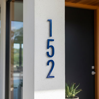 blue Modern house number '152' on a concrete pillar with a blurred background