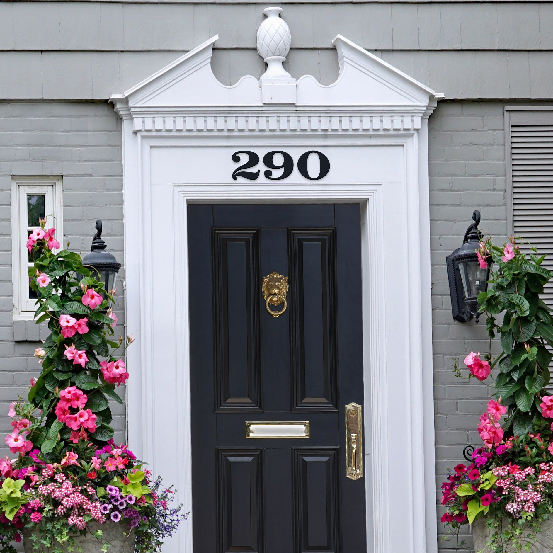 black house numbers above a black and brass door and painted grey brick house