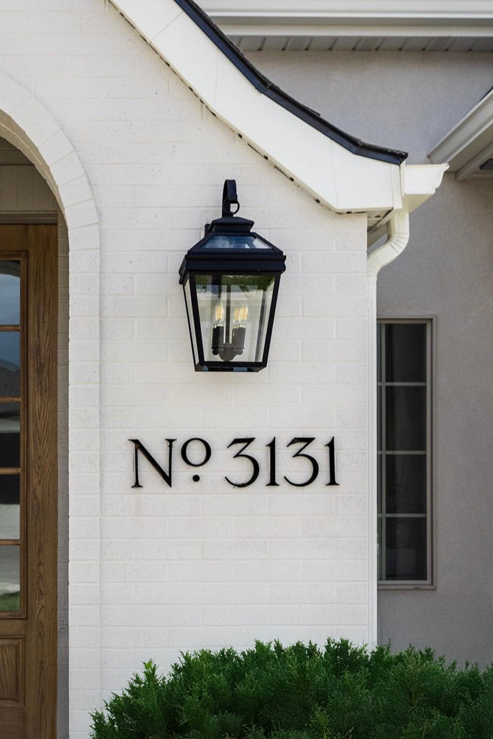 House exterior with a black lantern light fixture and house numbers 'No 3131' on a white wall.