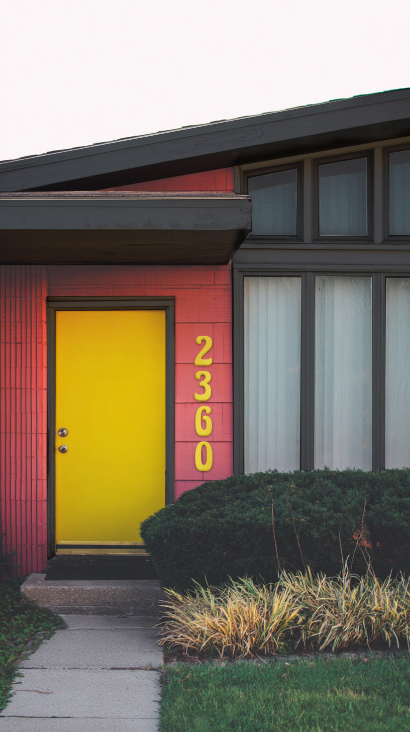 Modern house with a red exterior and yellow door yellow custom house numbers '2360' in a 1970's style house numbers
