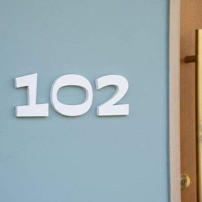 White house numbers '102' on a light blue door.
