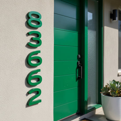 Green house door with house numbers '83662' on a light gray wall.