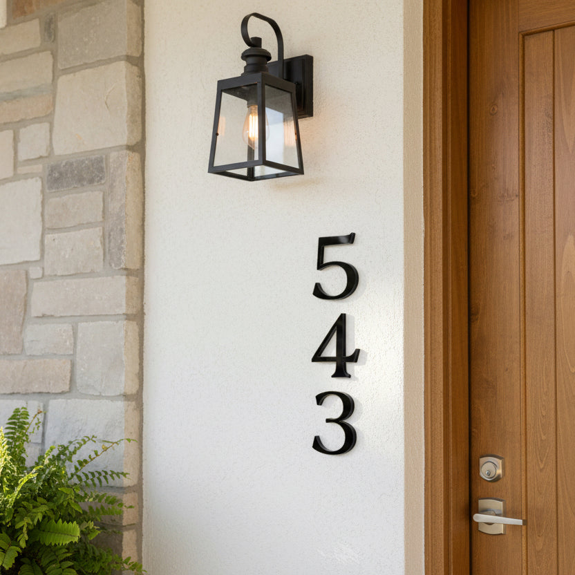 House numbers '543' on a white wall next to a door and light fixture.