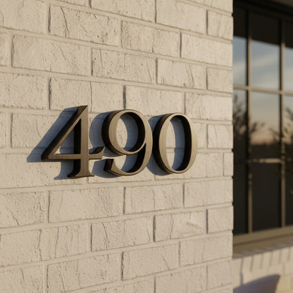 Bronze House numbers '490' on a beige brick wall