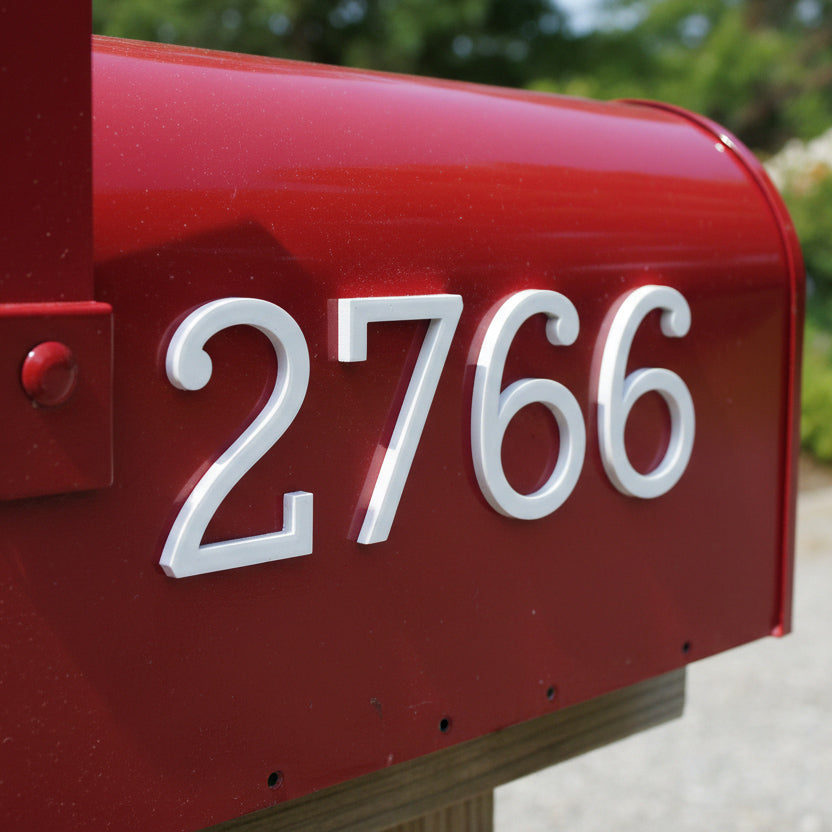 Red mailbox with white numbers '2766' against a blurred green background
