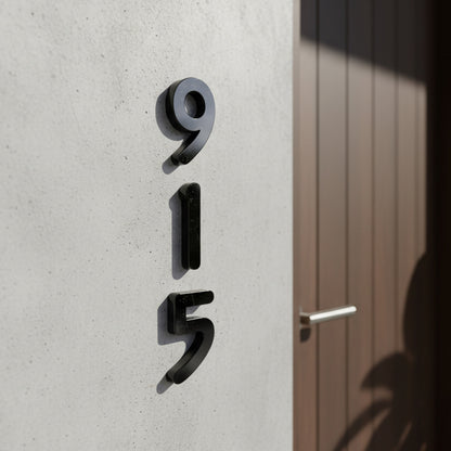 Black Modern house numbers '915' on a concrete wall.