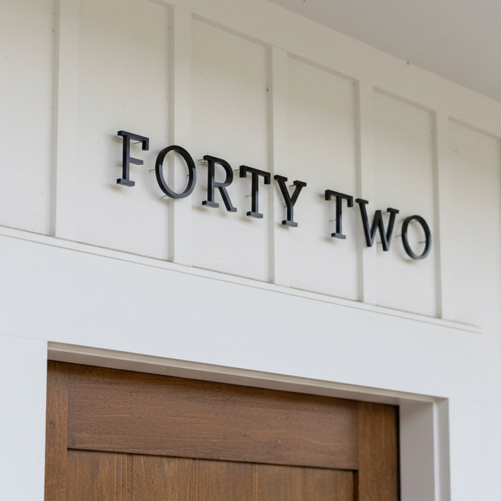 Decorative sign with 'FORTY TWO' on a white wall above a wooden door.