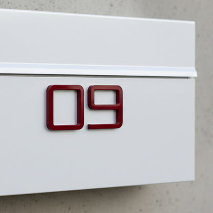 White mailbox with red numbers '09' on a concrete wall