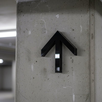 Black arrow symbol on a concrete wall