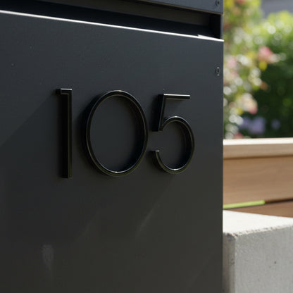 Black house number '105' on a modern mailbox with a blurred garden background