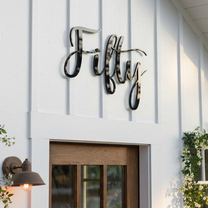 Decorative acrylic sign with 'Fifty' on a white building facade.