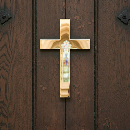 Gold cross with a central gemstone on a wooden door