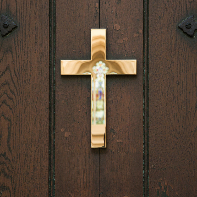 Gold cross with a central gemstone on a wooden door