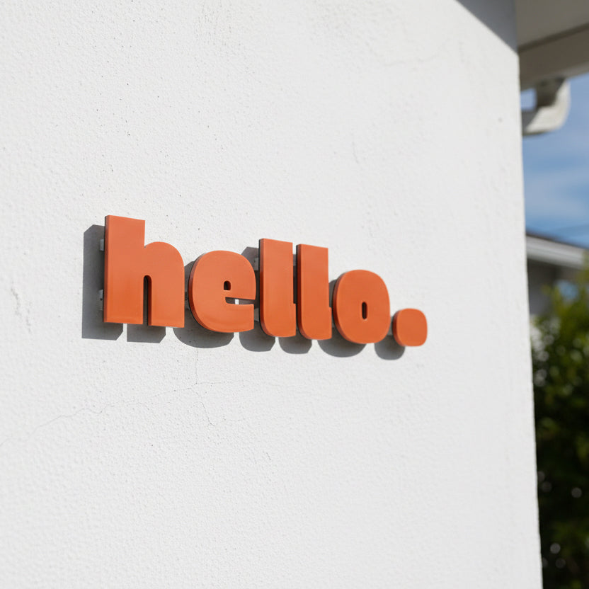 Orange 'hello' sign on a white wall