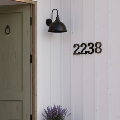 black House number '2238' on a white wooden door with a wall light fixture.