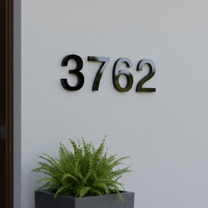 black House number '3762' on a wall with a potted plant below.